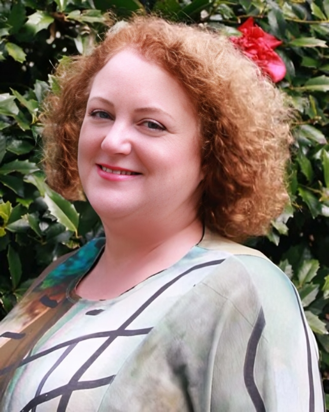 Smiling woman with curly hair outdoors.